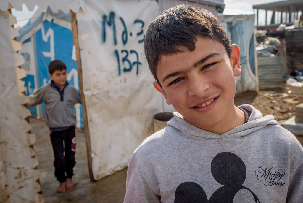 Ali, a Syrian refugee boy in the Bekaa Valley of Lebanon, stands outside his family’s tent