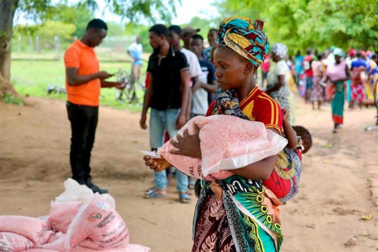 A mother with a her child in her back receives her portion of the seeds.