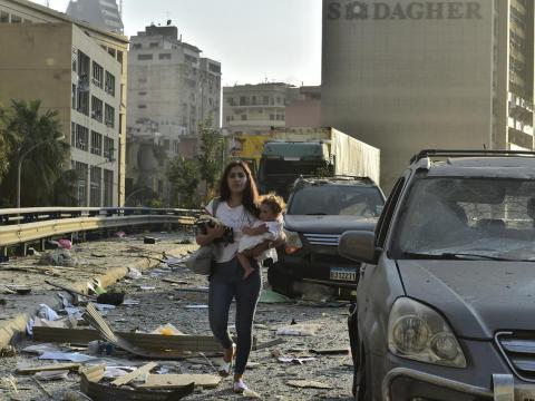 Woman walks with child through the streets of Beirut following blast