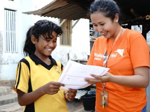 World Vision staff reads a letter from a sponsor with sponsored child