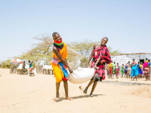 Beneficiaries carry food at a food distribution in Kenya