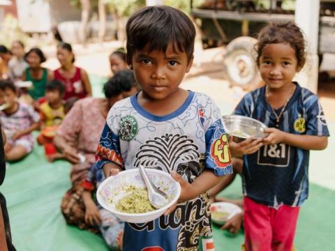 Children standing with food-filled bowls