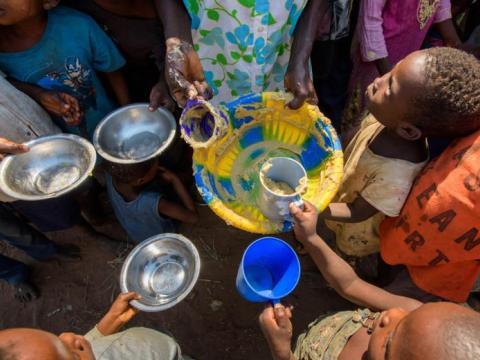 Children gather to receive mugs of food