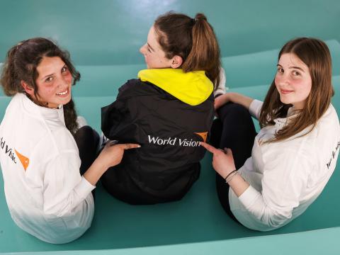 Girls pointing to World Vision logo