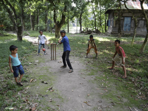 South Asian children playing cricket on a pitch