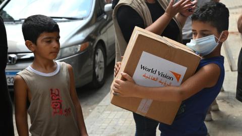 Child in Beirut carries a food kit distributed by World Vision
