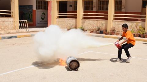 Palestinian Child Learning to use a fire extinguisher during a DRR activity in school