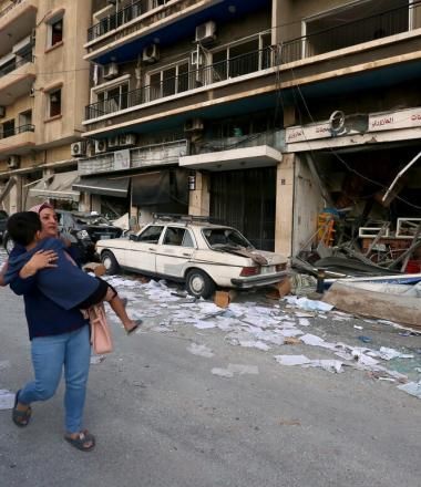 mother carries child through rubble along the streets of Beirut following deadly blast