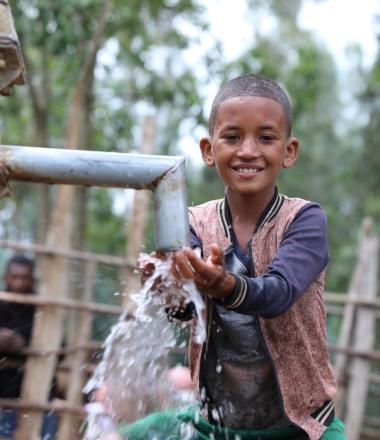 A Boy smiling at water point