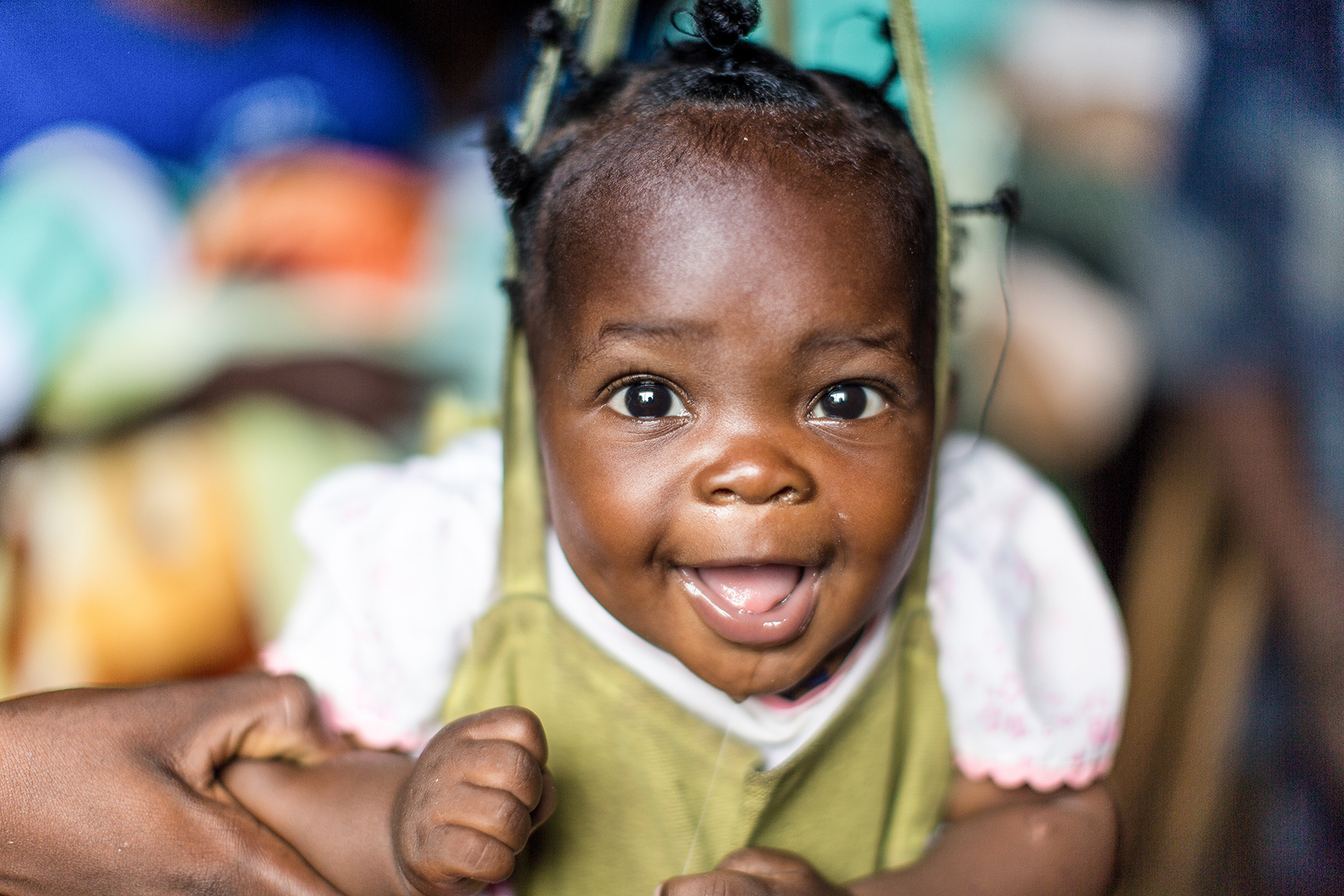 A baby smiles as she gets weighed