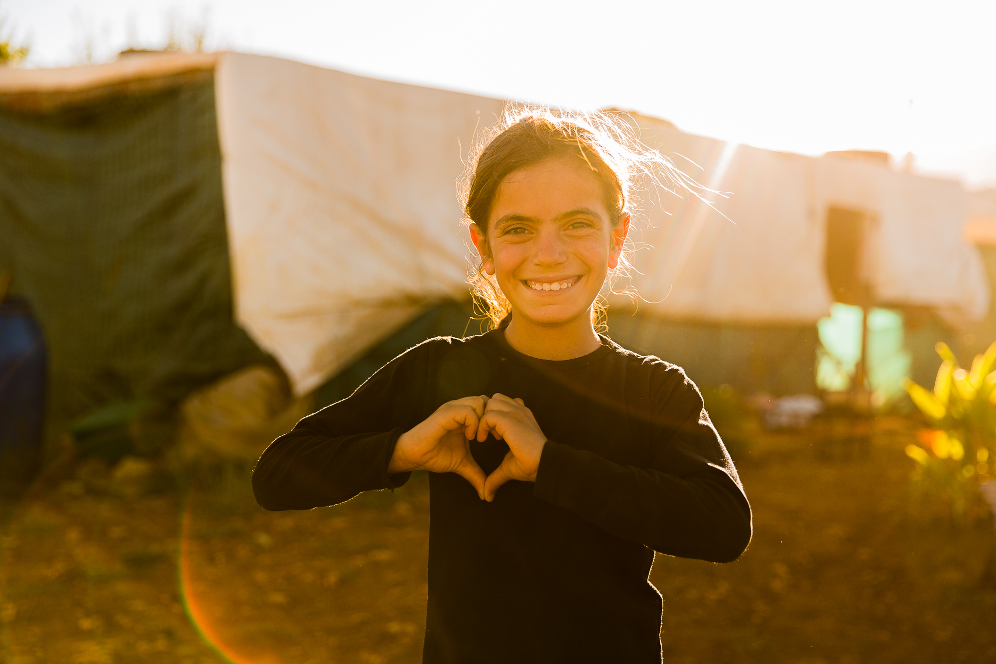 Syrian girl making a hear with her hands at sunset