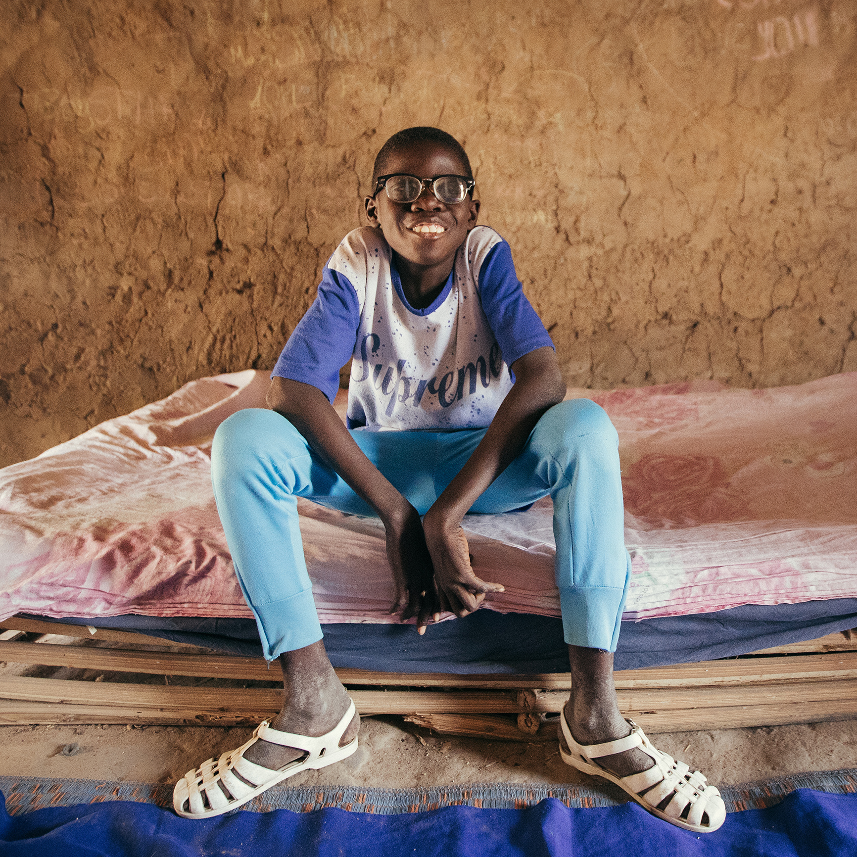 Boubacar sits on his bed in his room
