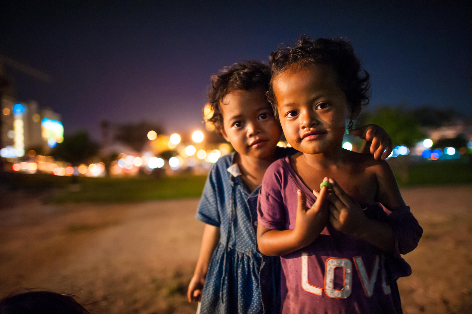 Two young Khmer children stand in the street