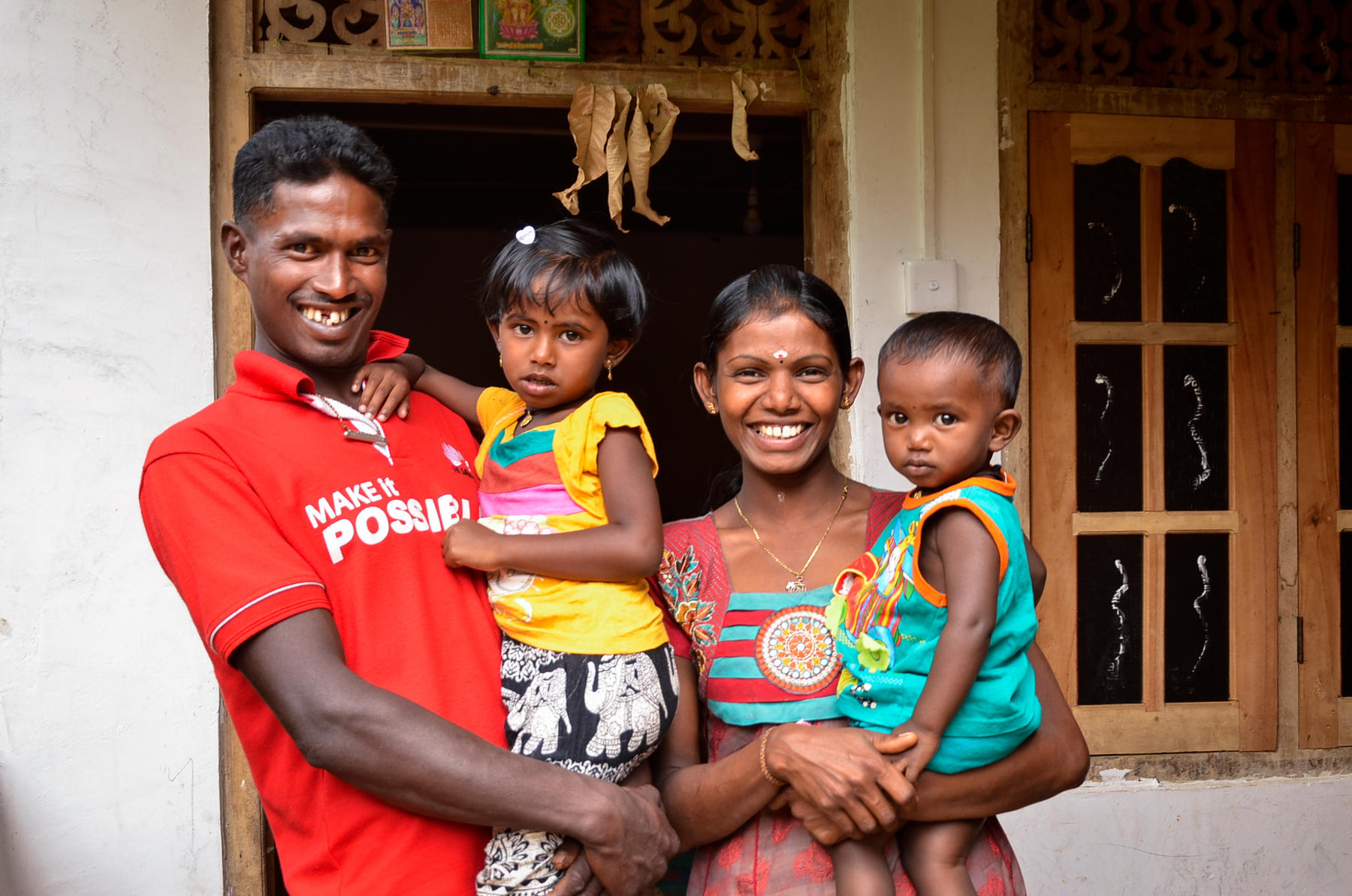 A sri lankan family smiles in front of their home