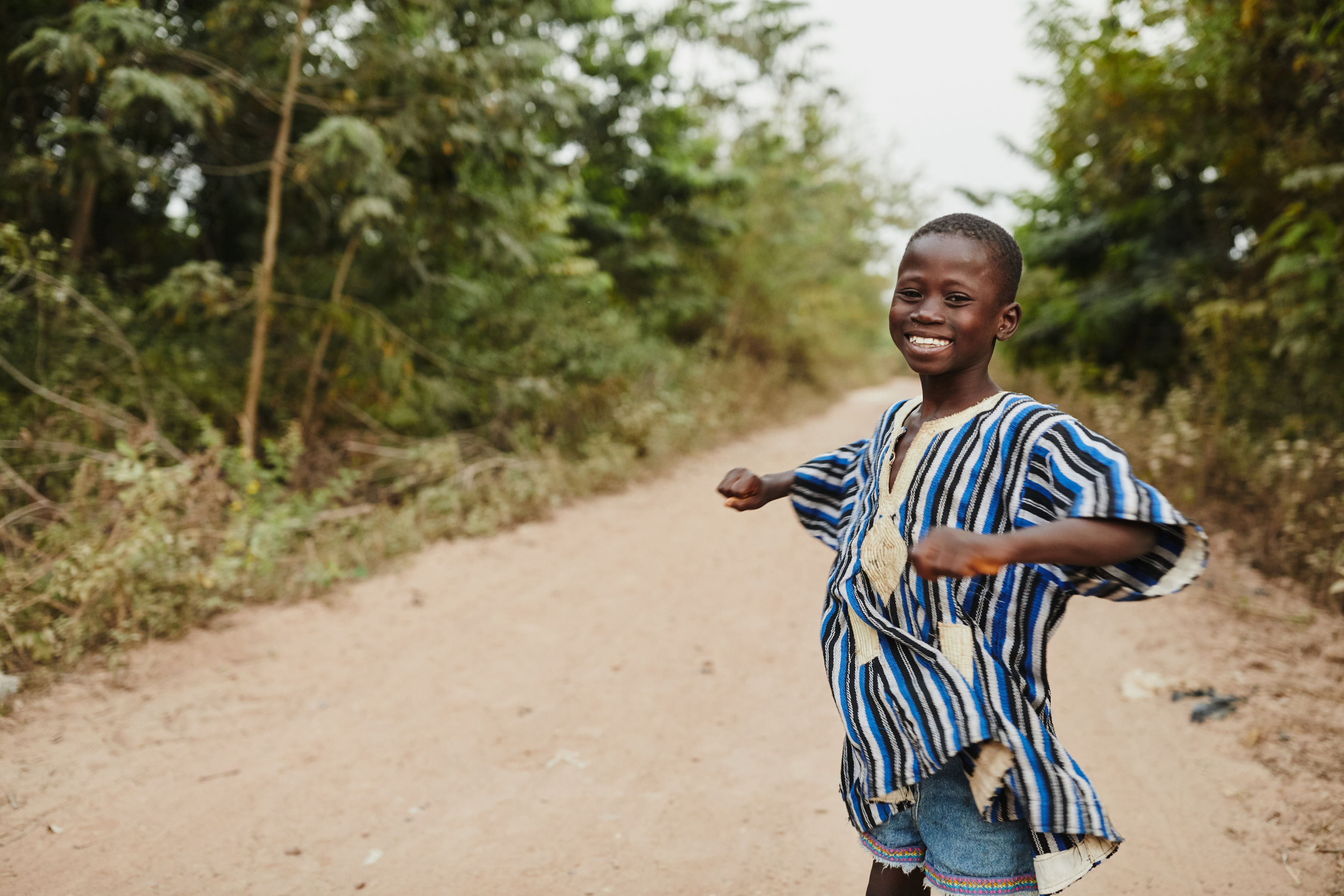 A boy dances on a road in Ghana