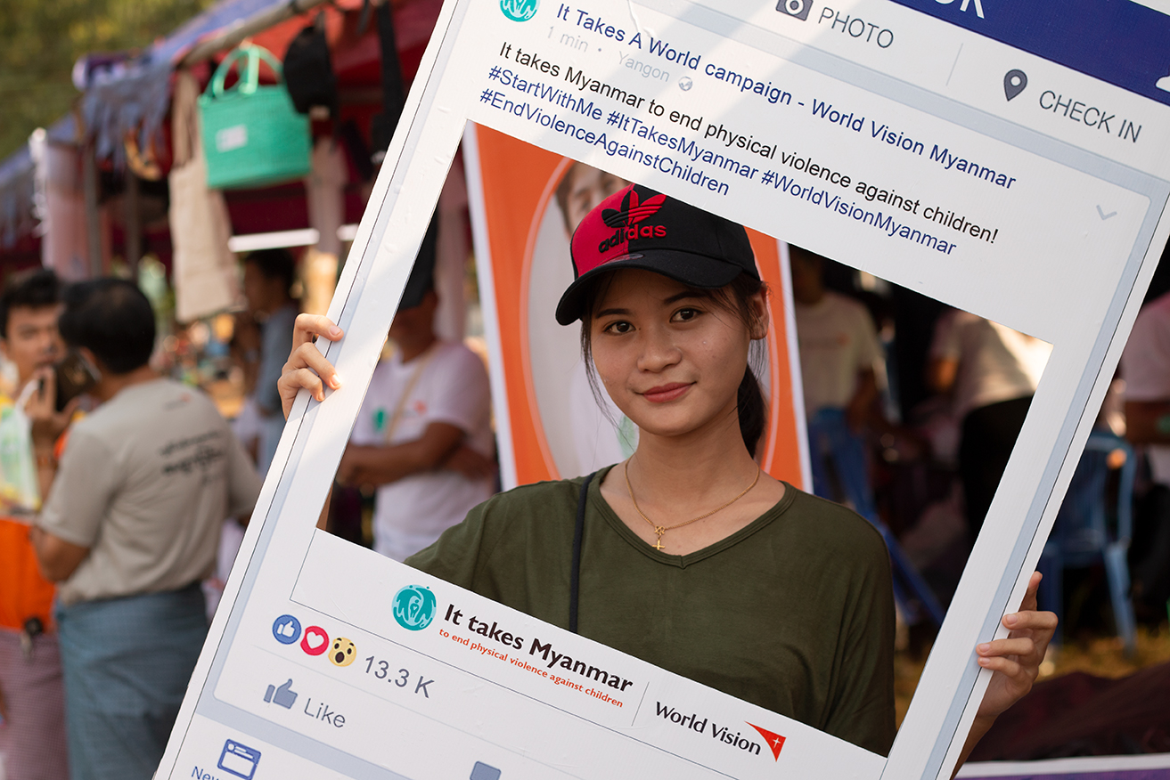 A woman holds an It Takes Myanmar sign