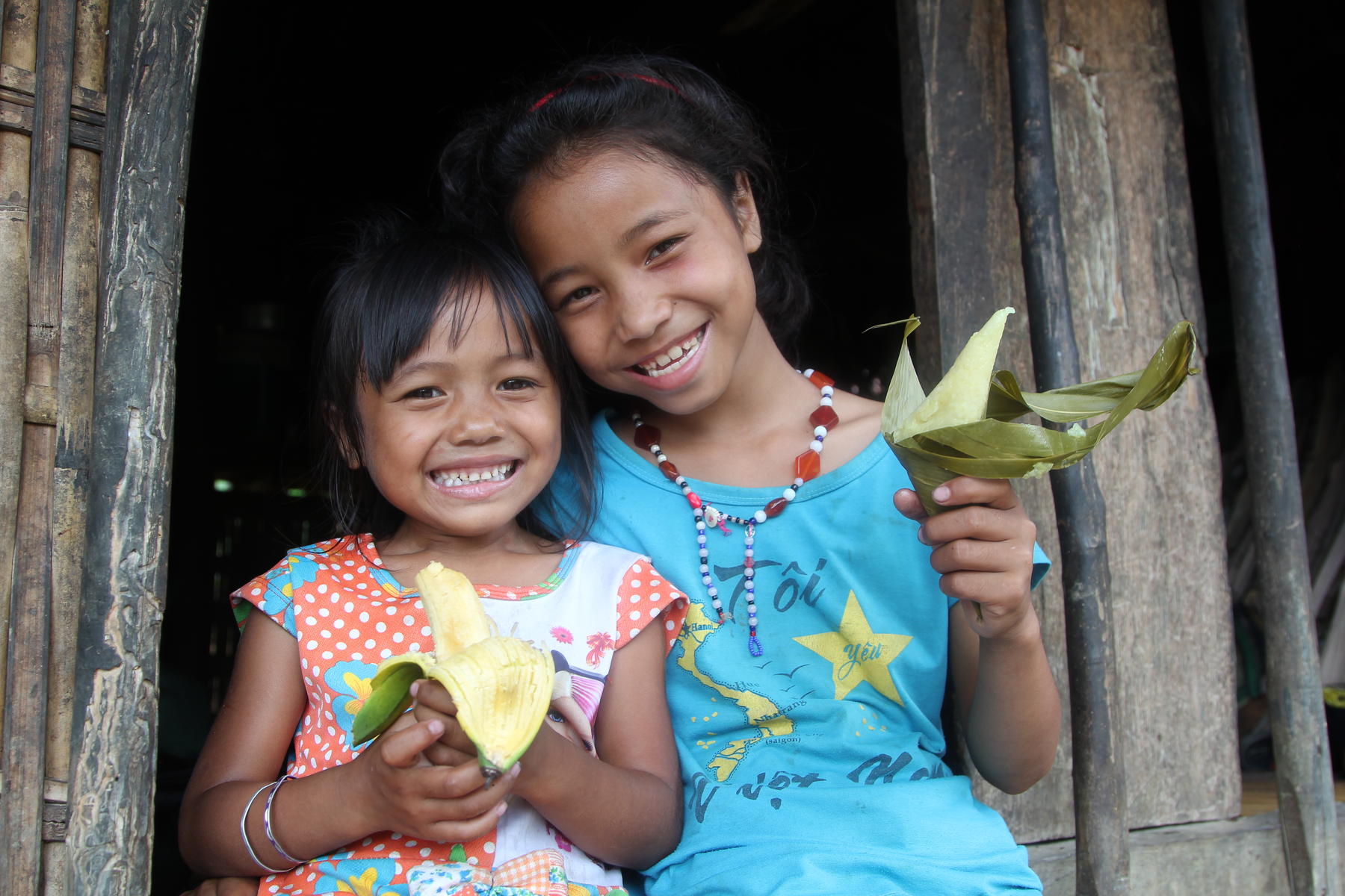 Two Vietnamese children hold flowers at their home