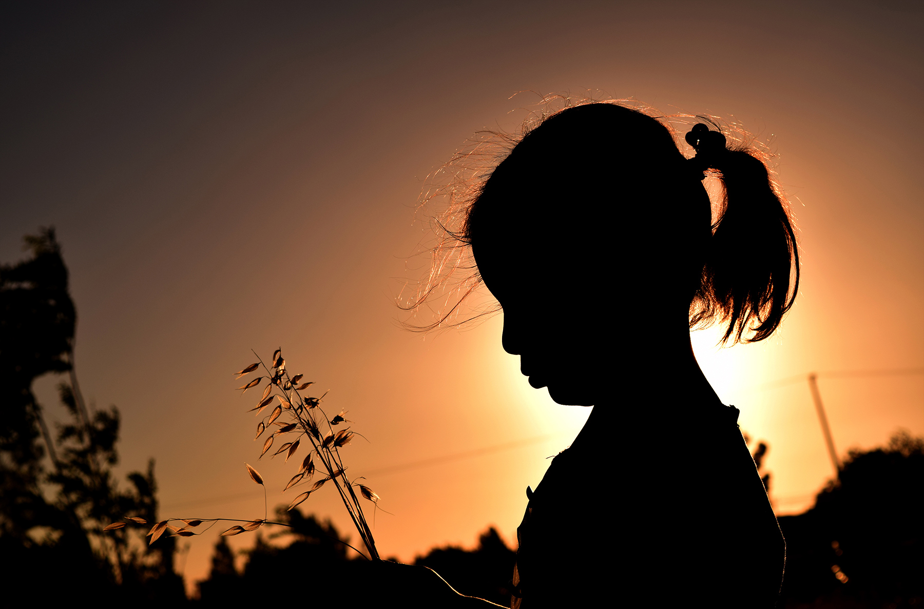 An afghan girl stands with the sun setting behind her
