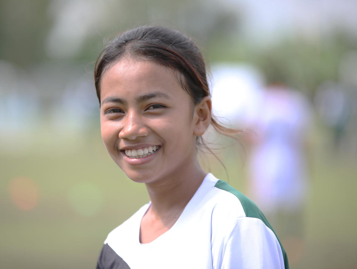 Khmer teenager in football jersey smiles on football pitch