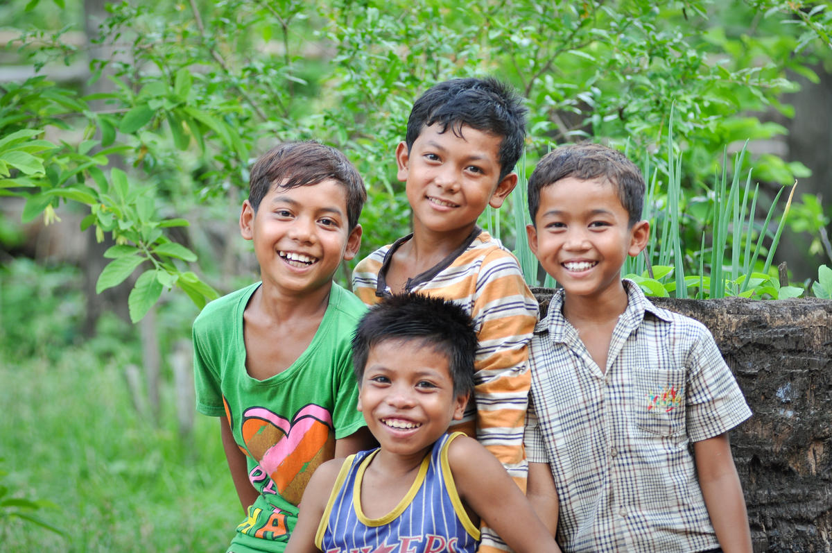 Four Khmer boys smiling at camera standing in garden