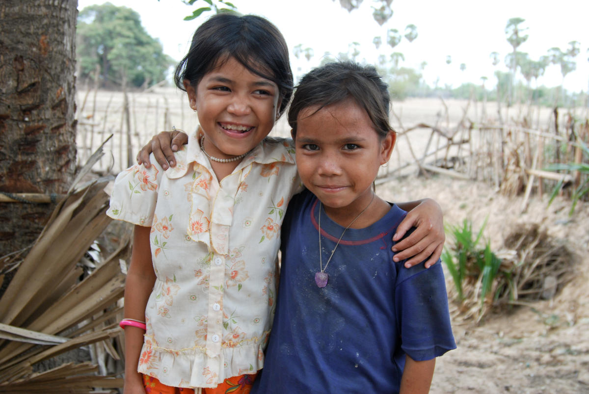 Two Khmer children stand together with their arms around each others shoulders