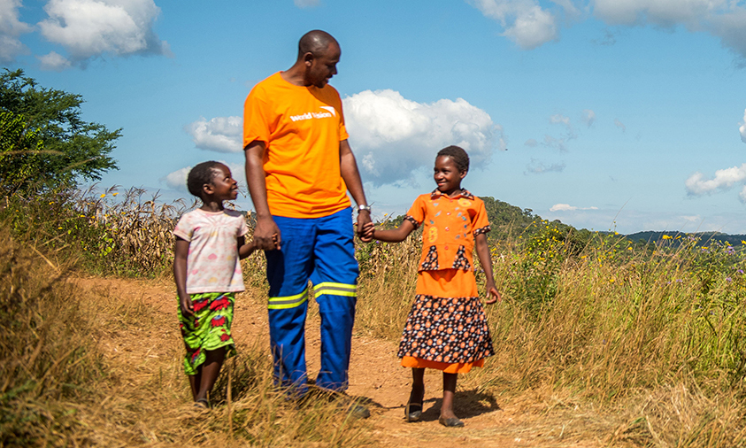 World Vision staff member walks with children in Africa