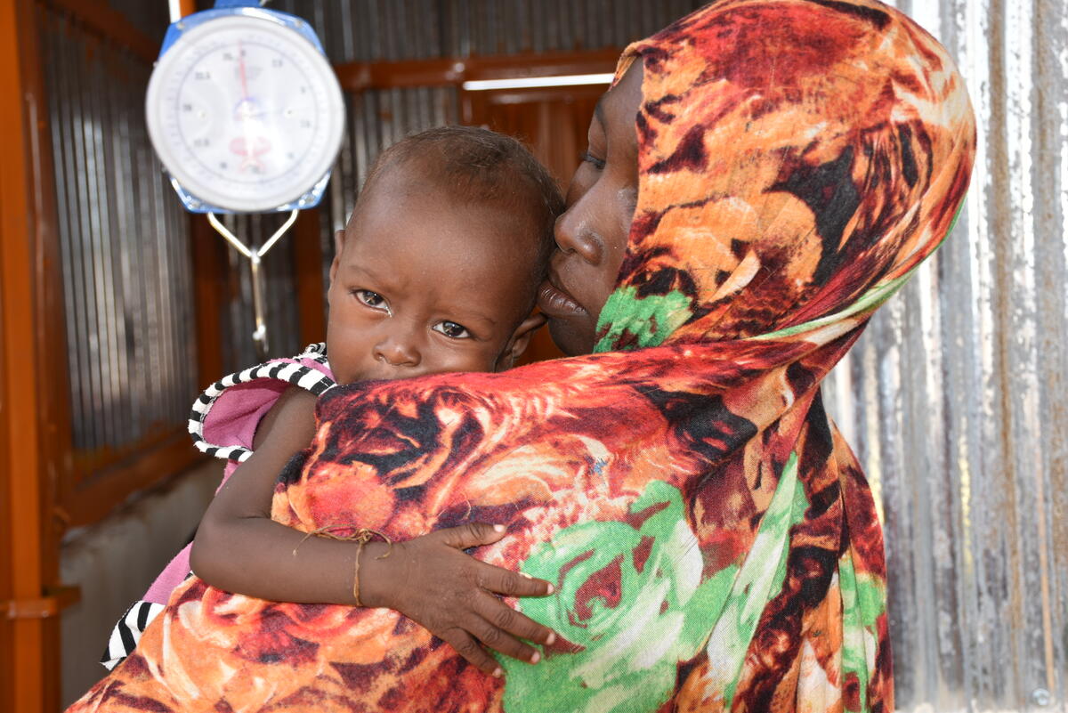 malnourished child on mother's shoulder