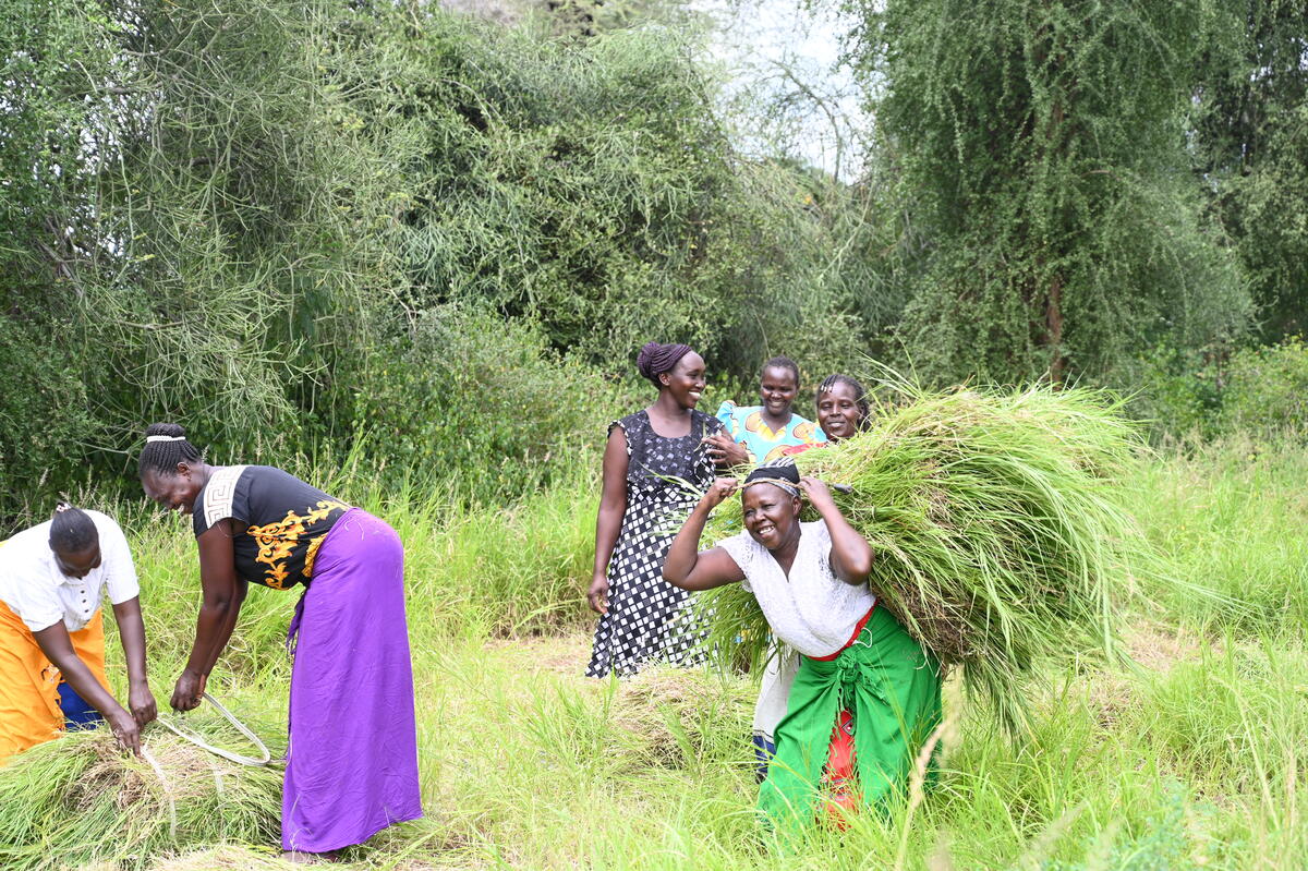 Women smiling as they collect crops in a field