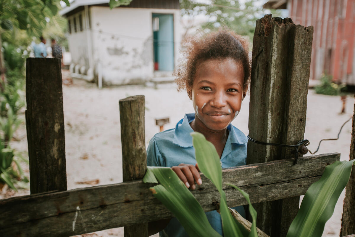 child stands behind fence