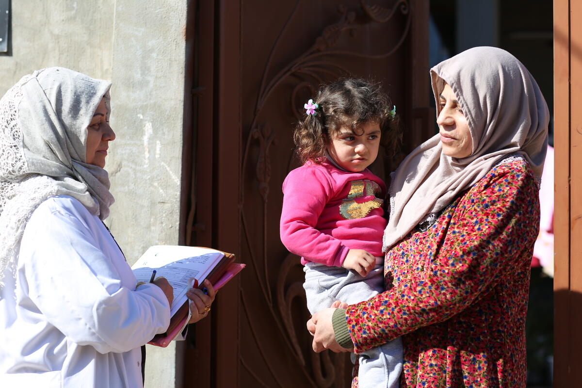 woman speaks to another woman holding a child during a door to door healthcare call