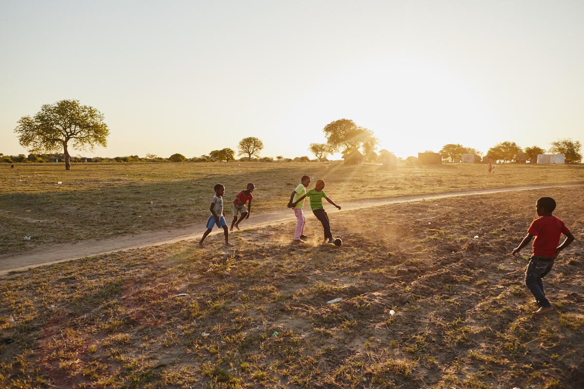 children play futbol in a dirt field
