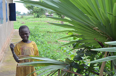 A young boy stands next to a World Vision Chad supported school for the girl-child, within Moundou region