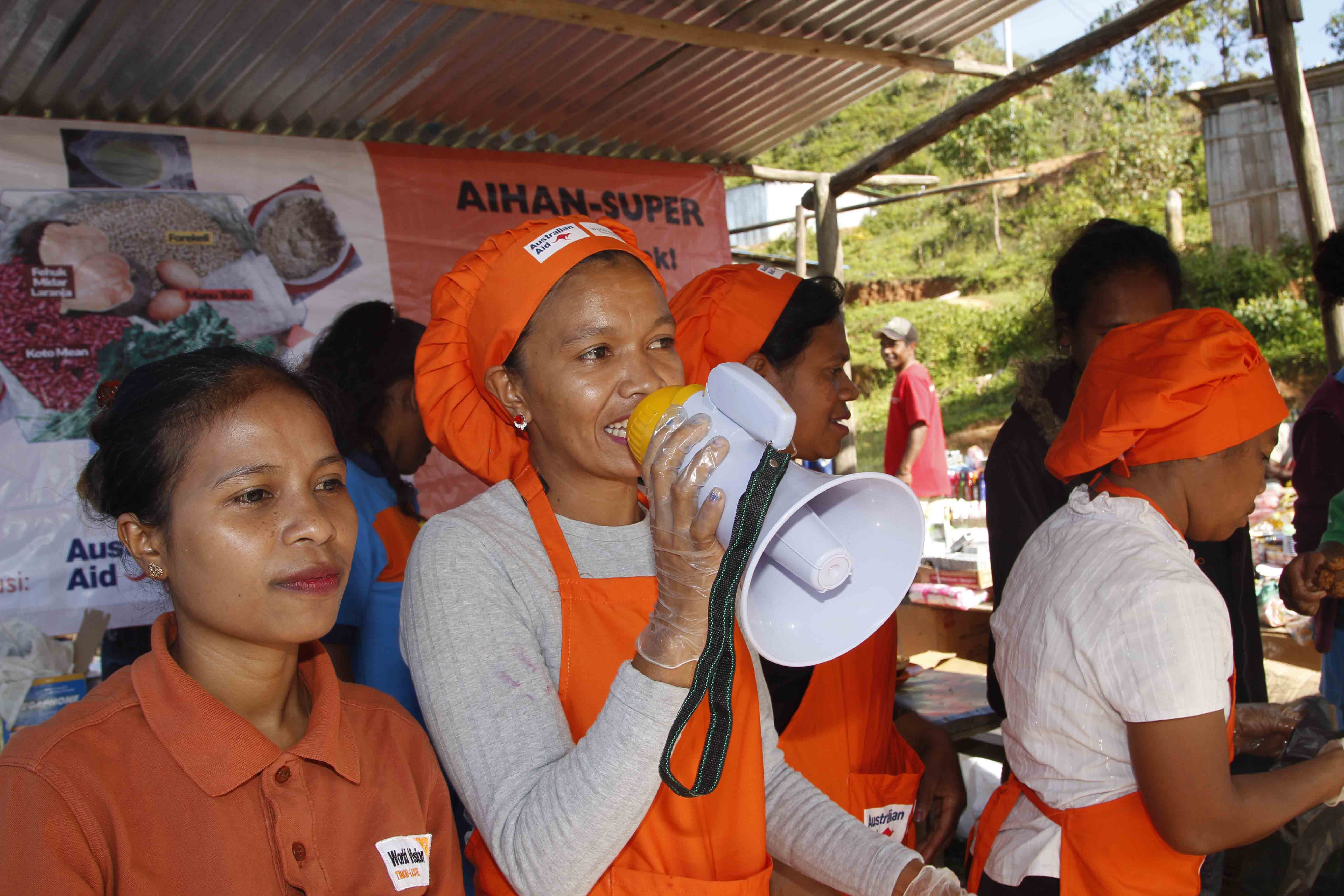 Terezinha uses a megaphone to sell her products at the market.