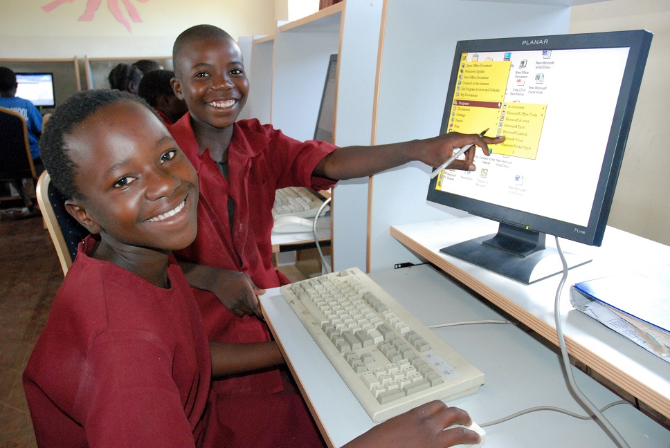 Children smiling in front of their computer terminal