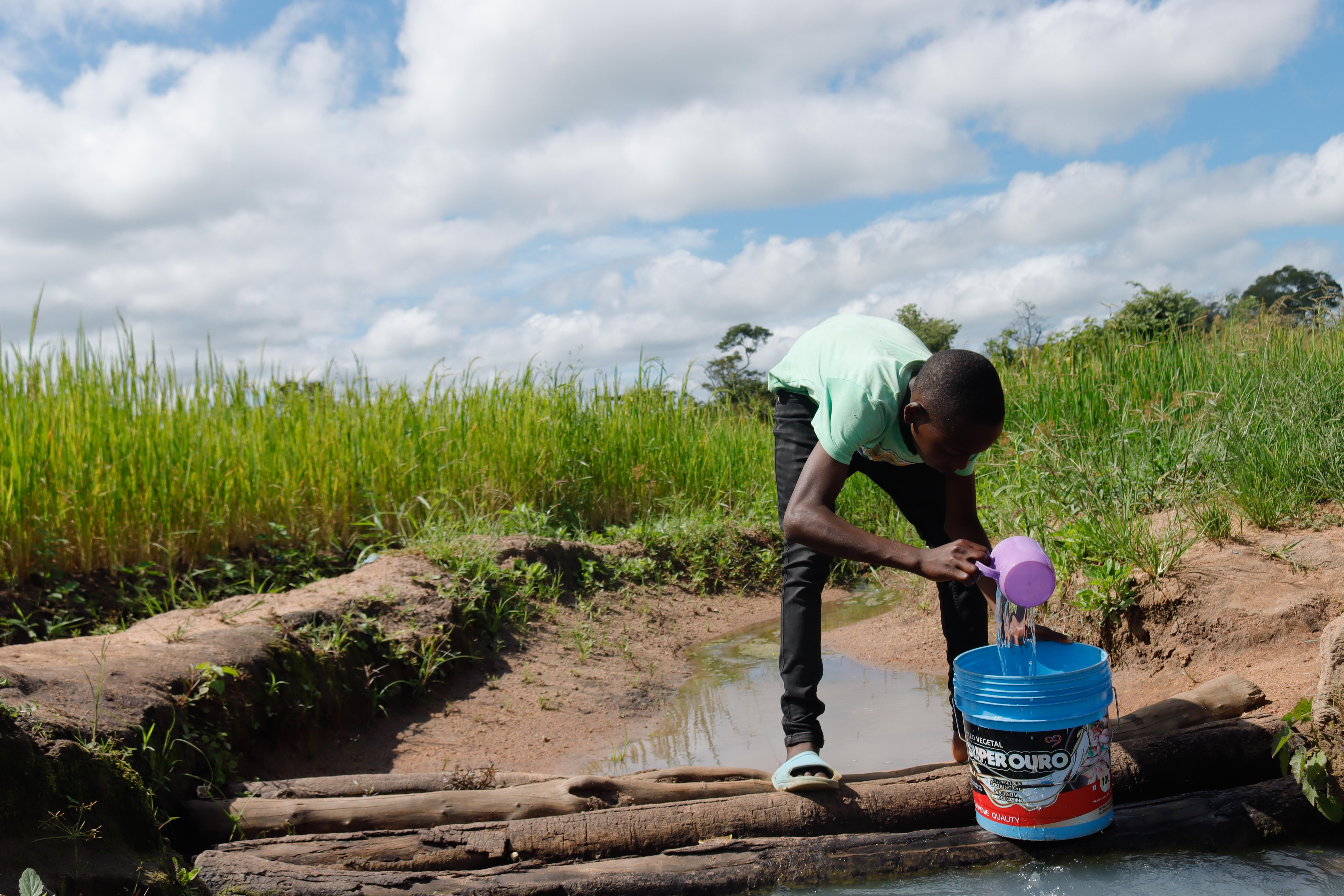 Samuel fills his bucket with water from the artisanal well dug by the community, which was the only water source available in the surroundings  