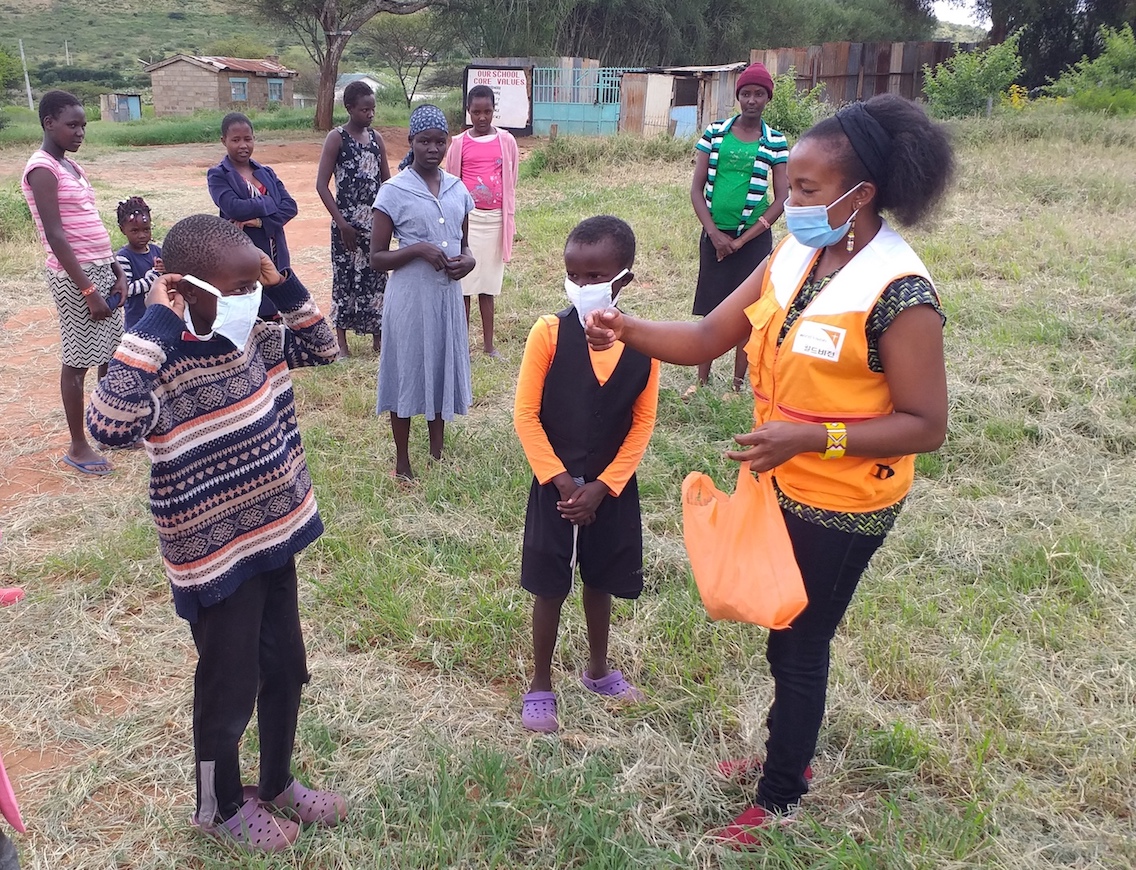 1-Marcos,10 (left) and Elijah, 10 (right) learning how to wear masks from Tabitha Mwangi. She is the Manager for World Vision's Osiligi Area Programme in Kajiado County, Kenya. 