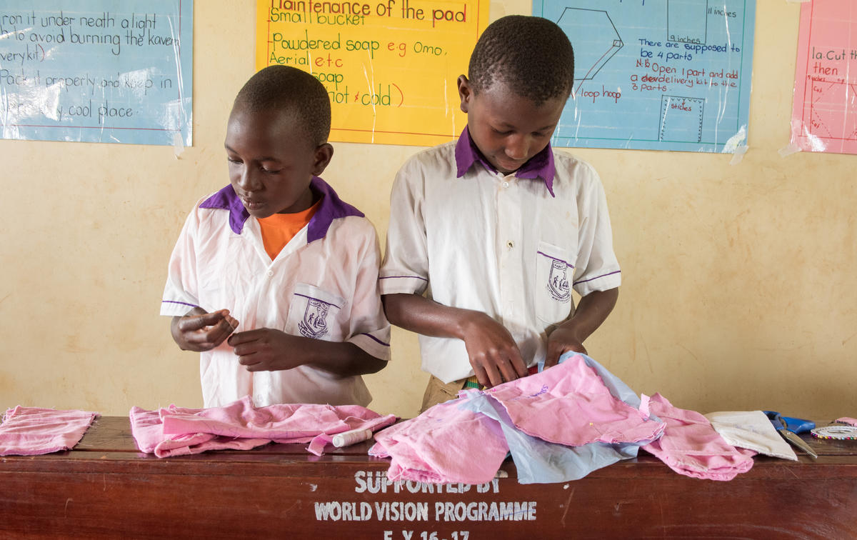 Boys in a World Vision Life Skills Club at a Ugandan primary school work alongside the girls making reusable sanitary napkins