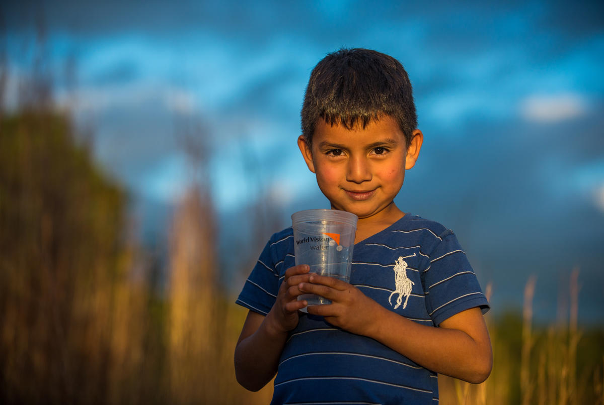 Christian, age 6, holds up clean water in a World Vision cup.