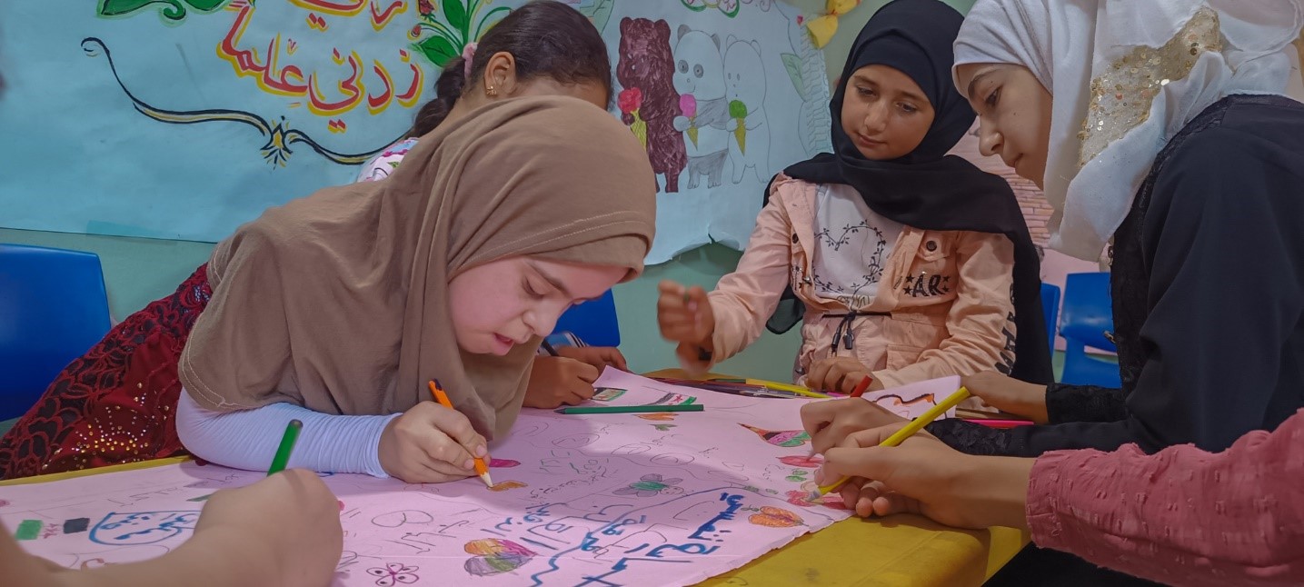 A photo of Bayan drawing with her peers captured by our partner Action For Humanity