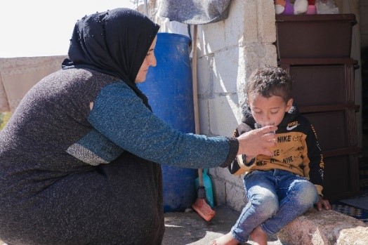 Sarah giving her son water. World Vision Syria Response Partner, ULUSLARARASI INSANI YARDIMLAŞMA DERNEĞI