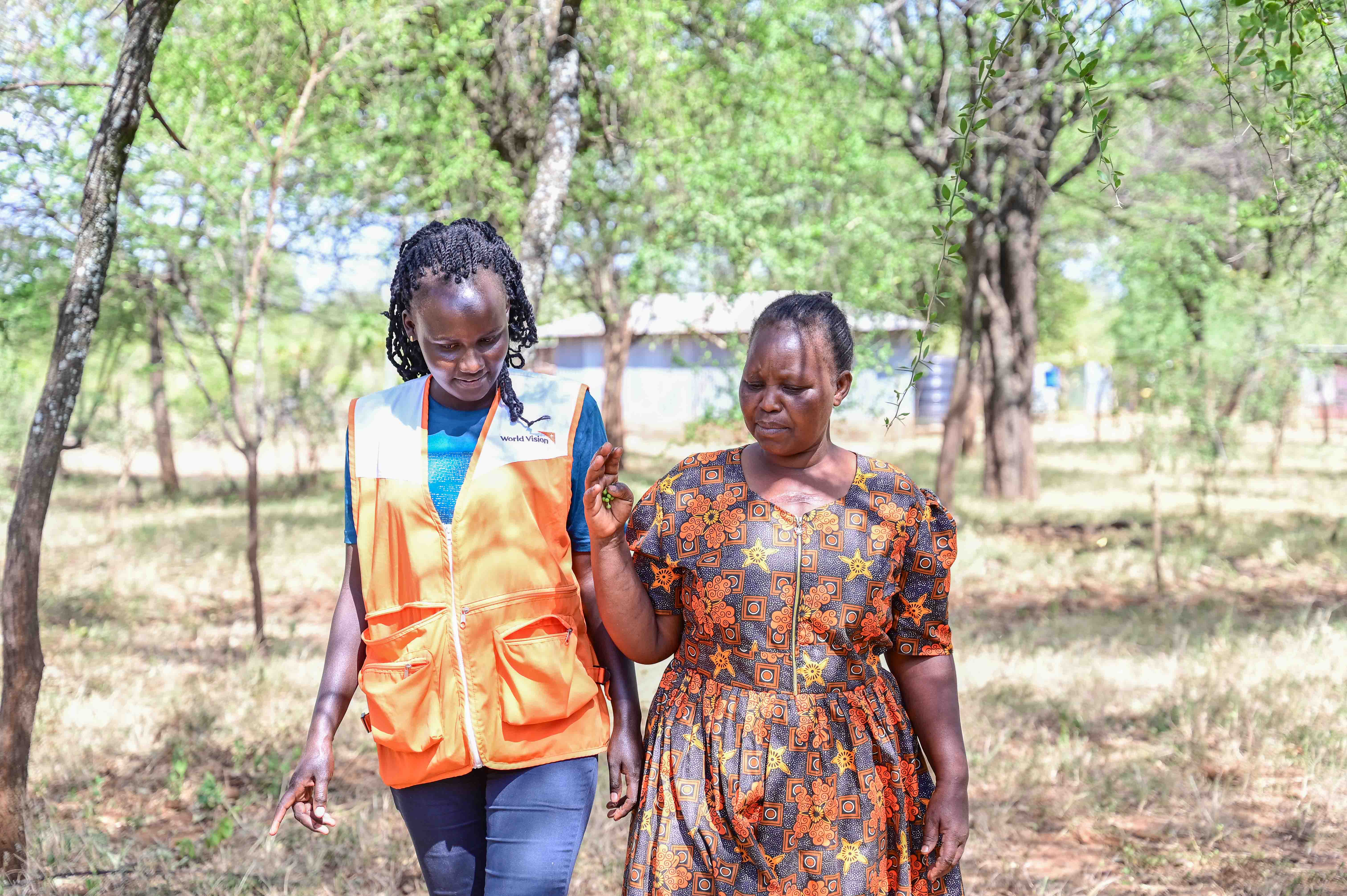 Selly in the company of Triza Kigen, World Vision Project Officer taking a walk in her FMNR farmland. ©World Vision Photo/ Hellen Owuor
