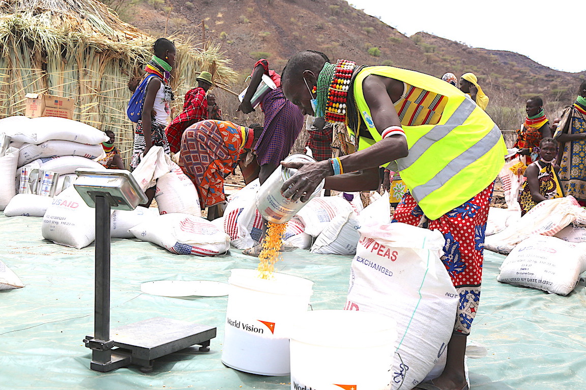 A community volunteer weighs food rations for distribution