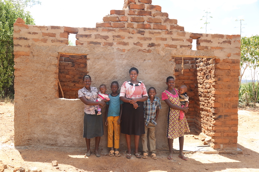 Janeffar and her family outside the new house that is being constructed using bricks 