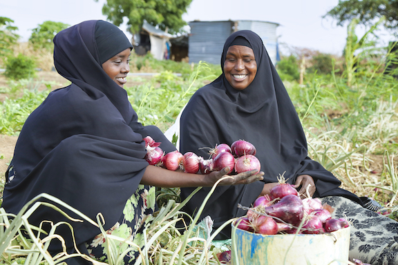 Kafia and Maimuna display onions that they are harvesting at Kafia farm. World Vision conducted training and provided farmers groups with small scale irrigation infrastructure and seeds. The farm is sustaining  families at this difficult time of drought. ©World Vision Photo/Martin Muluka.