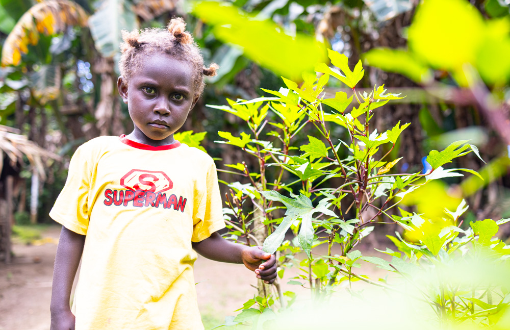 Jamaica standing smiling next to the backyard gardening