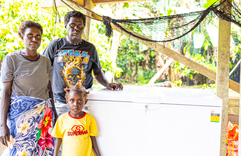 The family stands smiling beside their newly purchased deep freezer