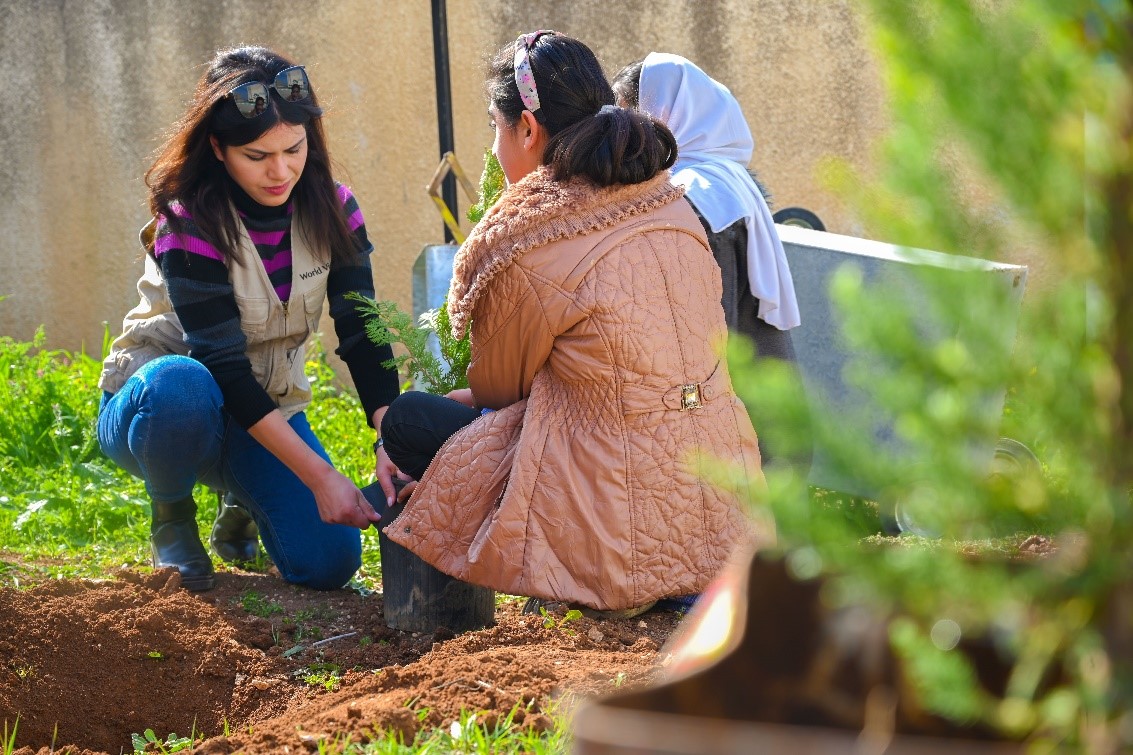 The project manager is engaging with students and helping them plant.