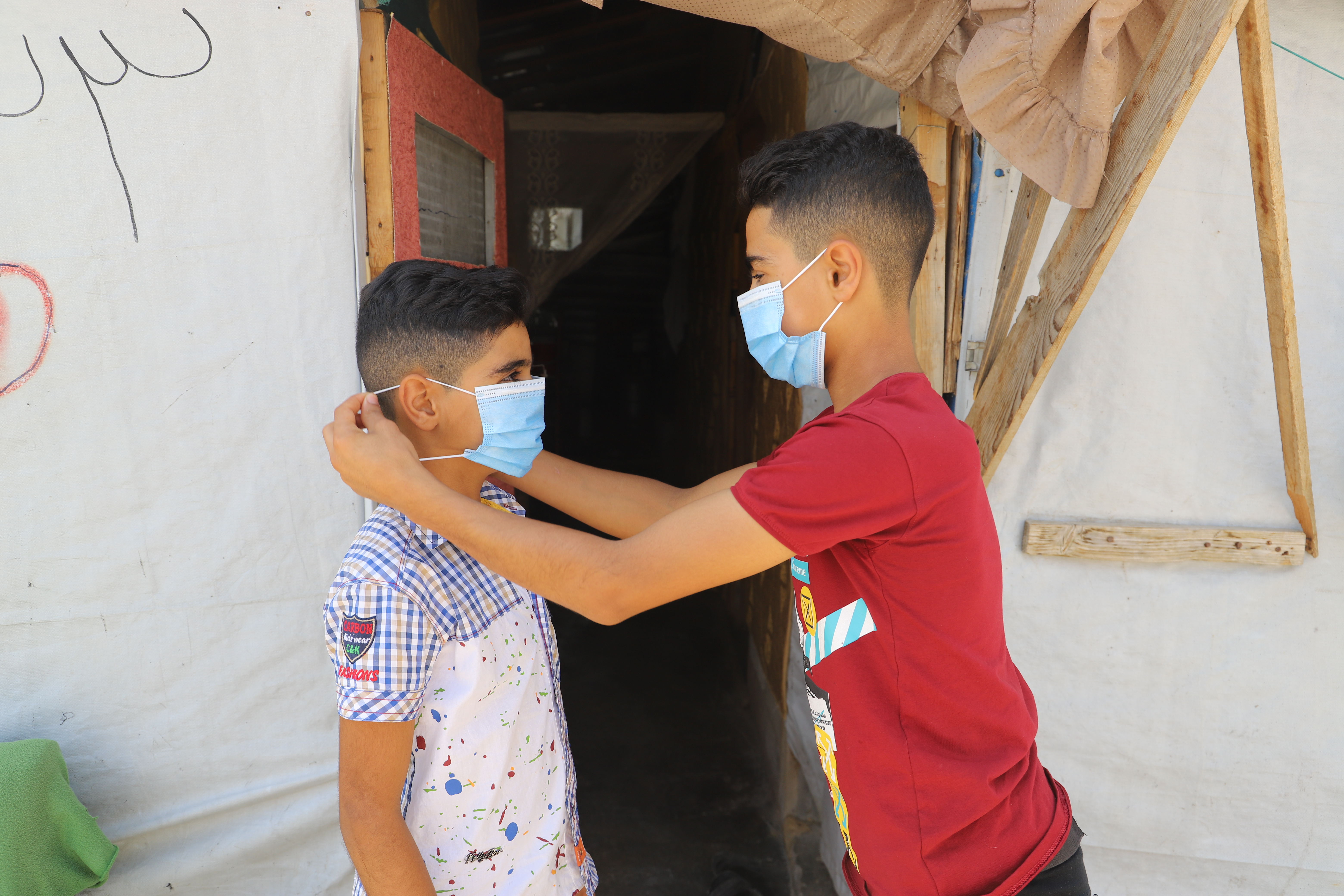 Ahmad putting a mask on his brother's face to keep him safe