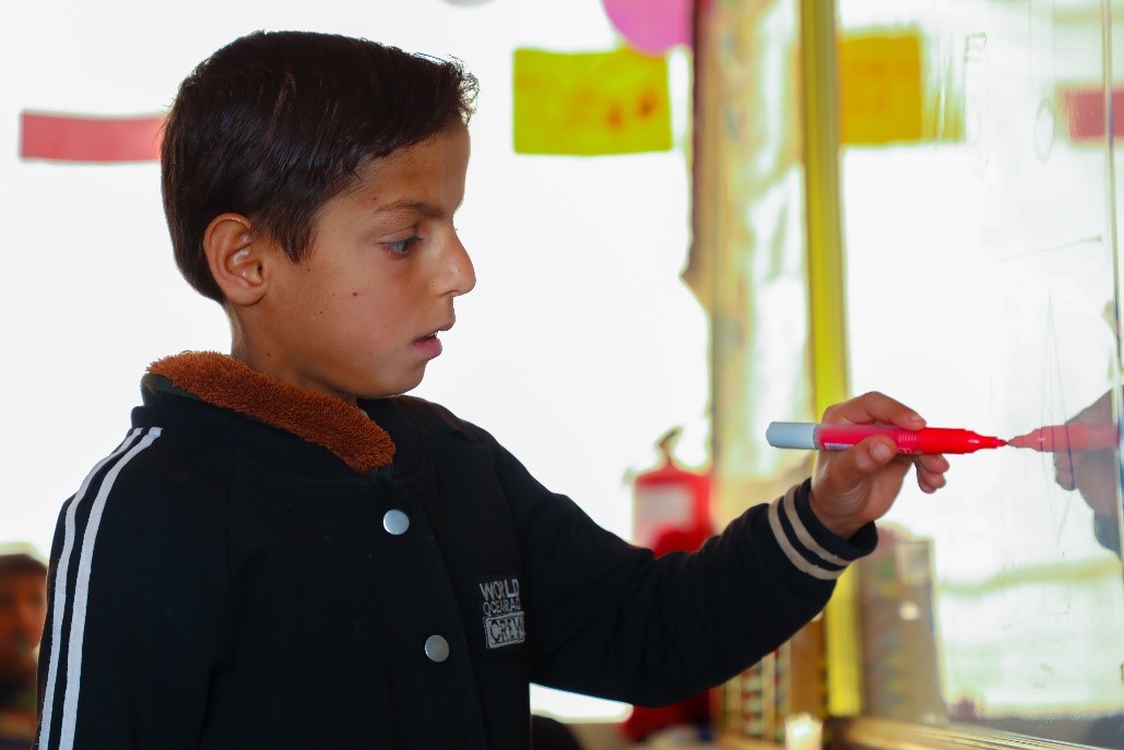 Faris writes on the board during class. ⒸWorld Vision Syria Response, Zaher Jaber