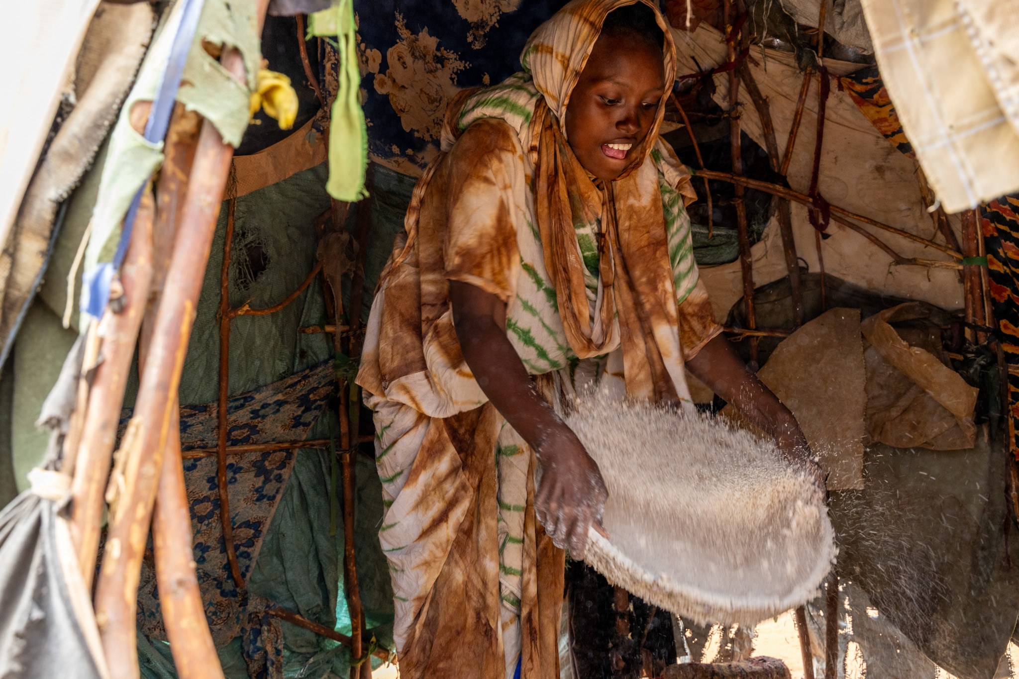 Muslimo winnowing millet, preparing it for breakfast with quiet determination.